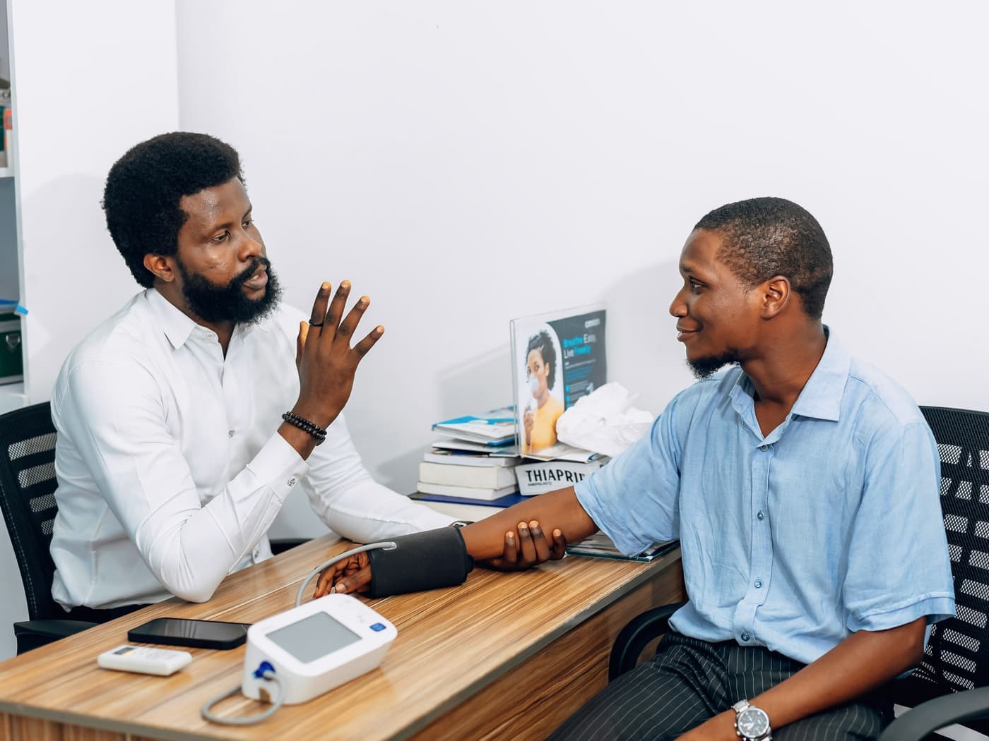 A doctor talking with a patient during a blood-pressure check at a clinic desk