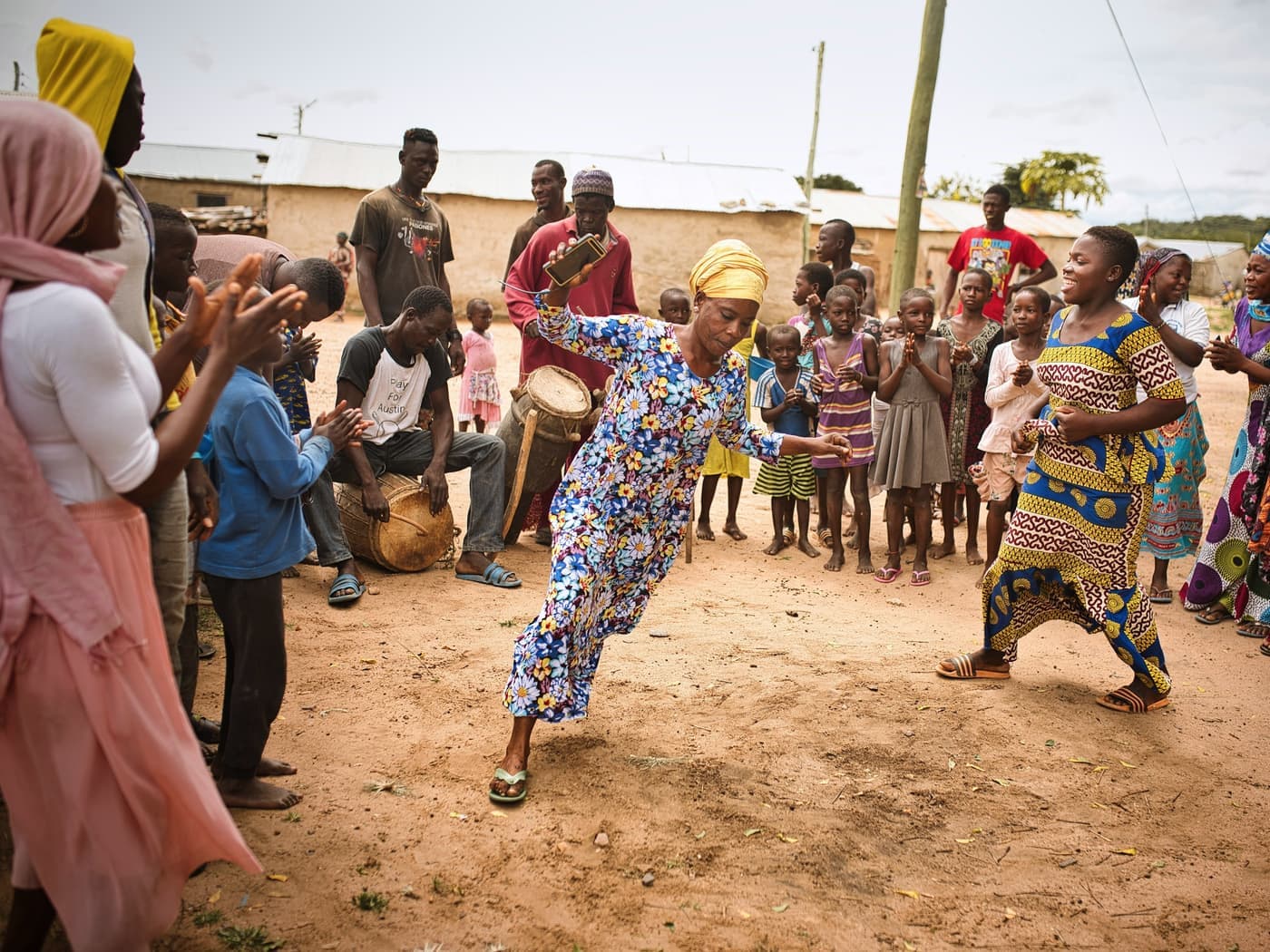 A community gathering with dancers and drummers in an open courtyard