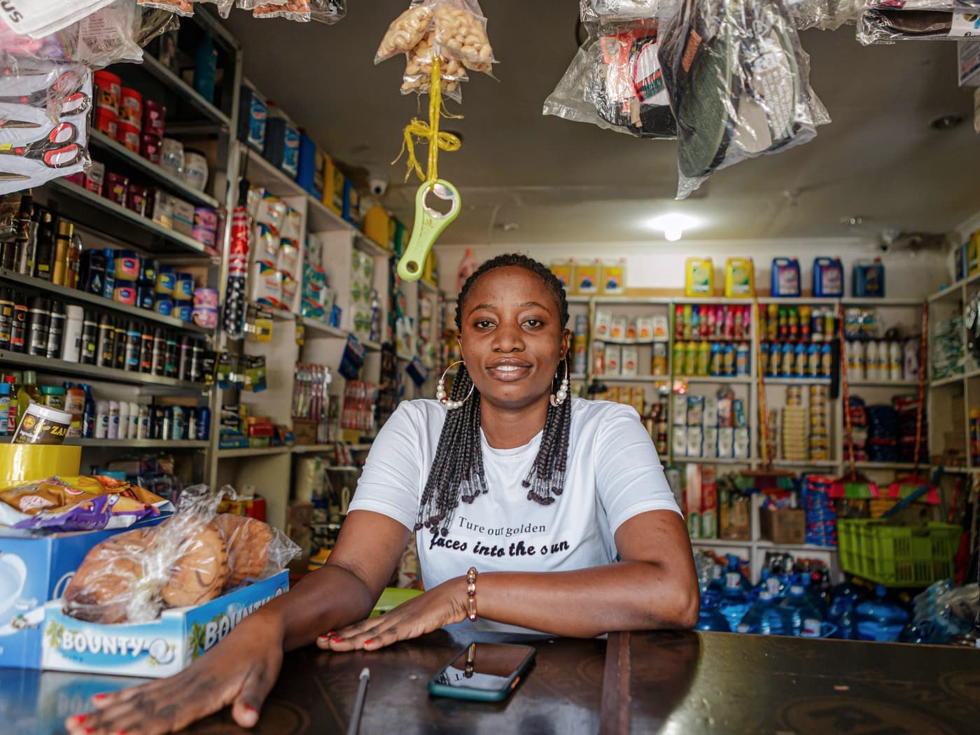 A smiling shop owner behind the counter of her grocery store